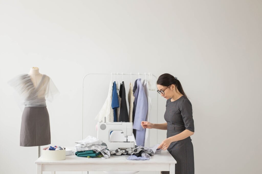 People and fashion concept - Young dressmaker woman sews clothes on sewing machine